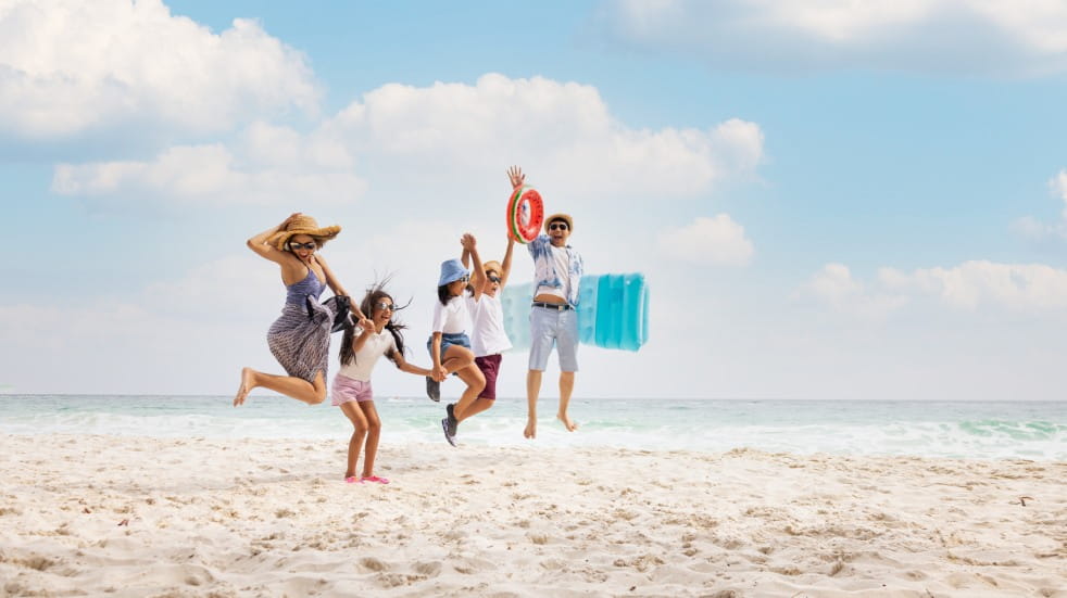 Family jumping on sunny beach